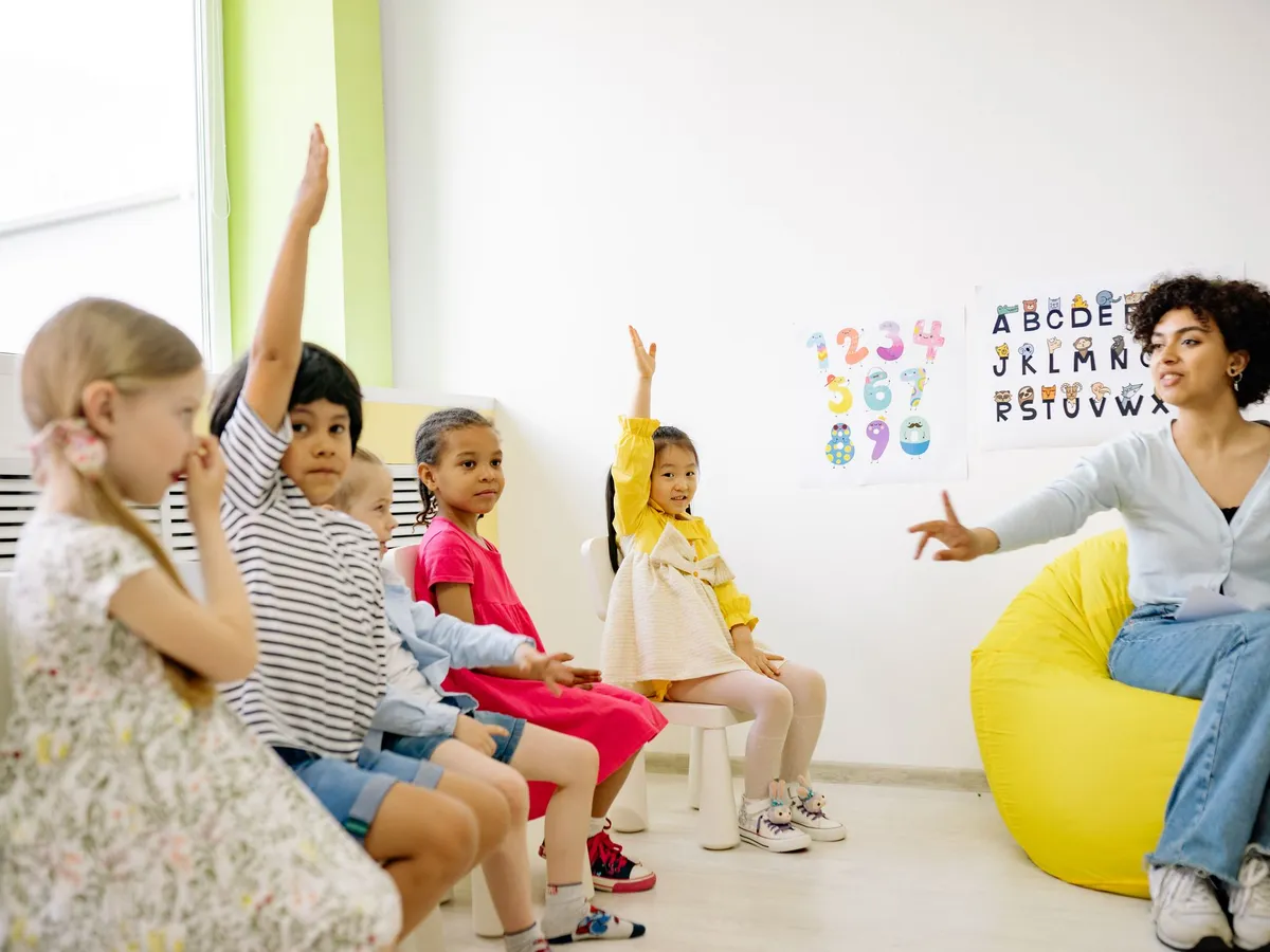 Preschoolers raising their hands during circle time with their teacher